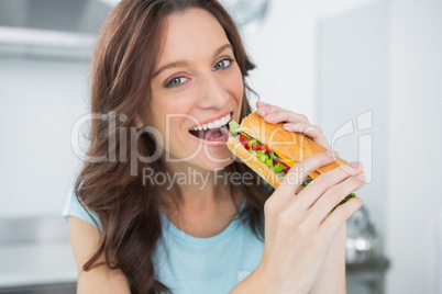 Cheerful brunette eating sandwich