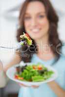 Healthy brunette offering salad