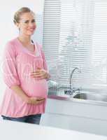 Cheerful expecting woman touching her belly