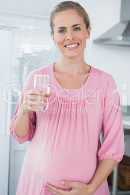 Cheerful expecting woman drinking water