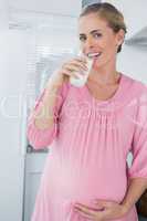 Happy expecting woman drinking milk