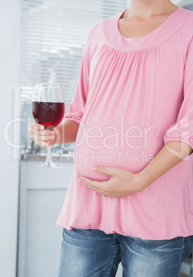 Expecting woman with glass of red wine