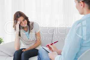 Worried woman sitting while therapist looking at her