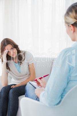 Worried woman sitting with therapist taking notes
