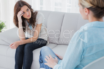 Upset woman sitting on the couch and looking at therapist