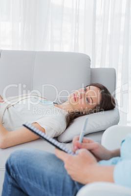 Upset brunette lying on the couch with psychologist at her side