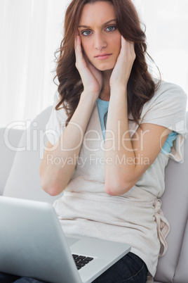 Anxious brunette working on her laptop