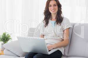 Relaxed brunette with laptop on her knees