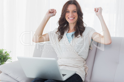 Cheering woman with laptop on her knees