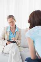 Psychologist listening to her patient and taking notes