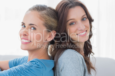 Cheerful women sitting back against back