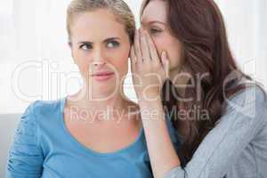 Blond woman hearing a secret from her friend