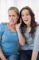 Disillusioned friends listening to mobile phone