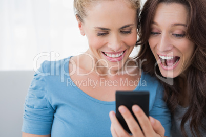 Cheerful friends reading message on their phone