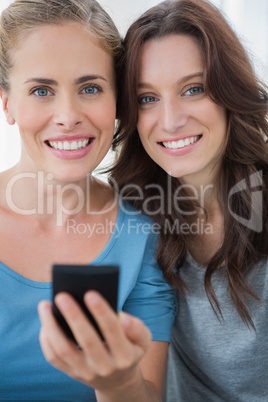 Smiling friends with mobile phone