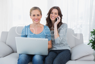 Women posing while using their laptop and phone