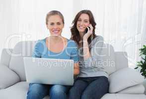 Women posing while using their laptop and phone
