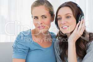 Brunette wearing headphones with her friend listening