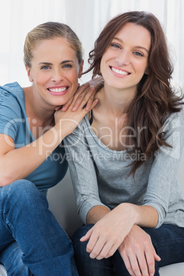 Delightful friends posing while sitting on the couch