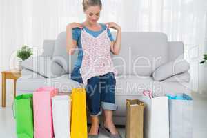 Blond woman with shopping bags trying out a top