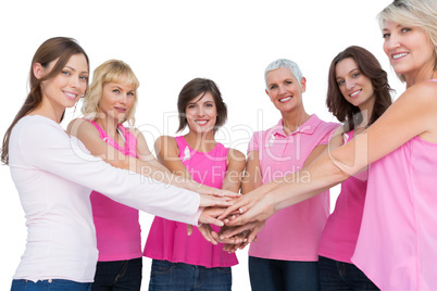 Cheerful women posing in circle holding hands looking at camera
