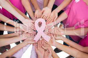 Hands joined in circle holding breast cancer struggle symbol