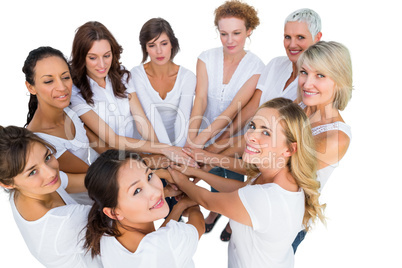 Female models joining hands in a circle and looking at camera
