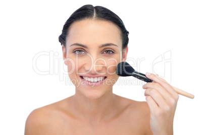 Smiling natural model applying makeup on her face