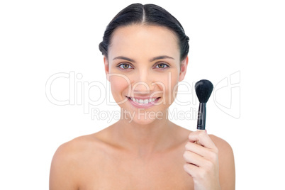 Cheerful natural model holding powder brush