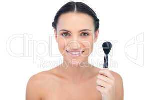 Cheerful natural model holding powder brush