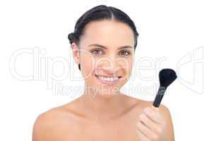 Smiling natural model holding a powder brush