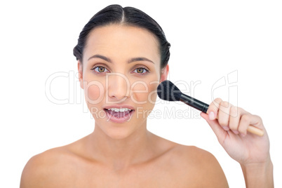 Smiling natural brunette applying powder