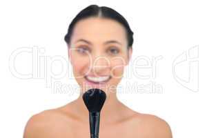 Delightful natural brunette holding powder brush