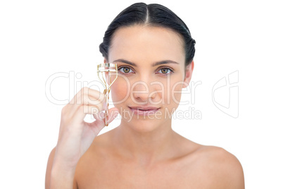 Smiling natural brunette holding eyelash curler