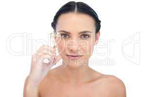 Smiling natural brunette holding eyelash curler