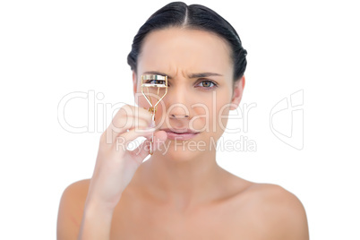 Serious natural brunette with eyelash curler