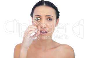 Astonished natural brunette with eyelash curler