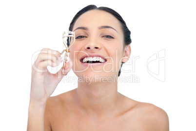 Smiling natural model with eyelash curler looking at camera