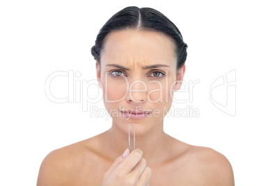 Frowning young model with tweezers