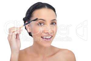 Surprised young brunette using eyebrow brush