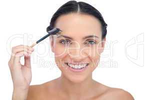 Cheerful young model using eyebrow brush