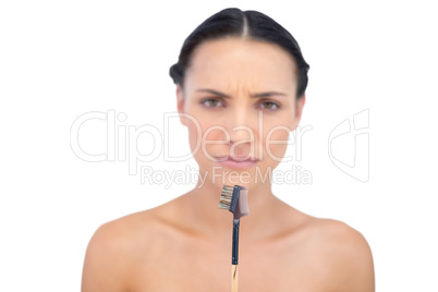 Frowning young model holding eyebrow brush
