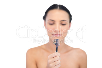 Beautiful young model holding and looking at her eyebrow brush