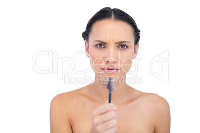 Serious beautiful young model holding eyebrow brush