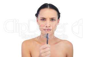 Serious beautiful young model holding eyebrow brush