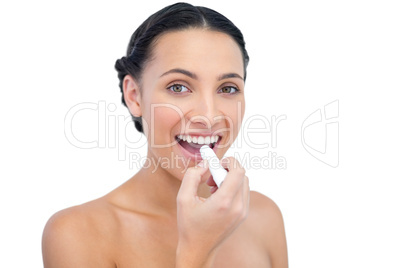 Enthusiastic young natural model applying lip balm
