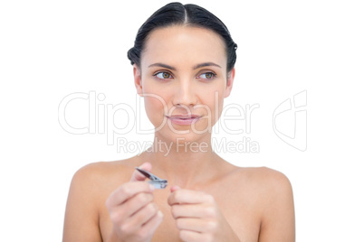 Thoughtful young model using nail clippers