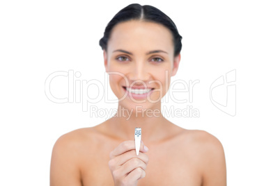 Smiling young brunette holding nail clippers