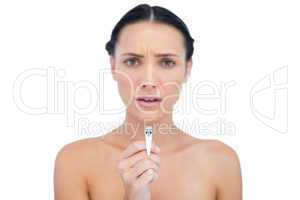 Frowning young brunette holding nail clippers