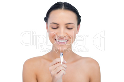 Happy brunette holding and looking at her nail clippers